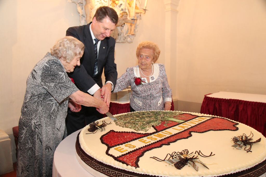 Pirmais Simtgadnieku Salidojums 2017. gadā. 3 cilvēki griež svētku kūku.Foto: Ingrīda Punka