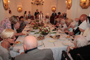 2017. gada Simtgadnieku Salidojums. Cilvēki sēž pie klāta galda. Foto: Ingrīda Punka