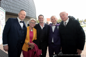 2025. gada Simtgadnieku Salidojums. Pieci cilvēki smaida. Foto: Kaspars Ūdris