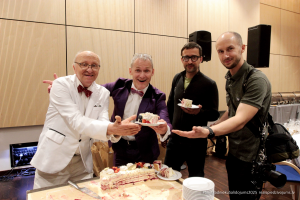 2025. gada Simtgadnieku Salidojums. Cilvēki ar svētku kūku. Foto: Kaspars Ūdris