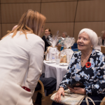 2025. gada Simtgadnieku Salidojums. Divas sievietes sarunājas un smaida. Foto: Edgars Krinbergs