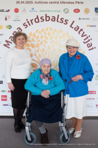 2025. gada Simtgadnieku Salidojums. Trīs sievietes smaida. Foto: Edgars Krinbergs